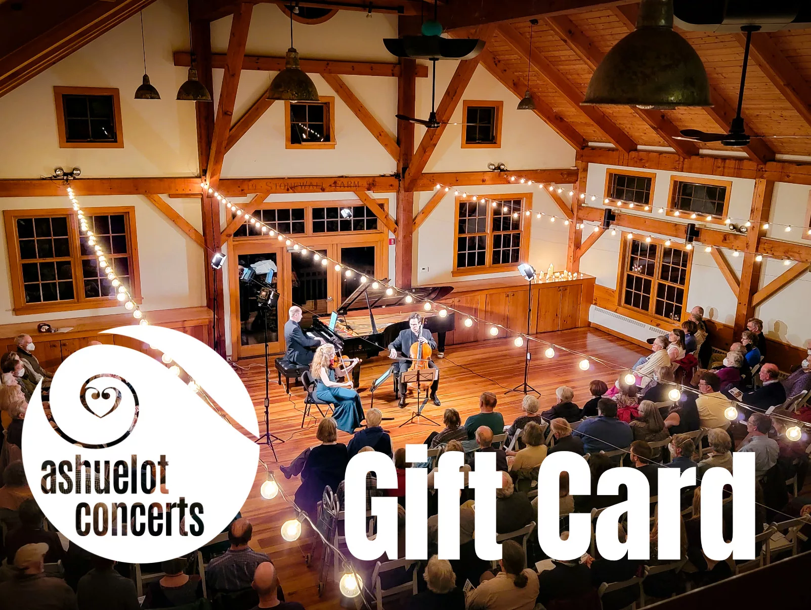 A string quartet performs on a small stage in a wooden hall, with an audience seated below hanging lights. Bold white text reads “Gift Card.”.