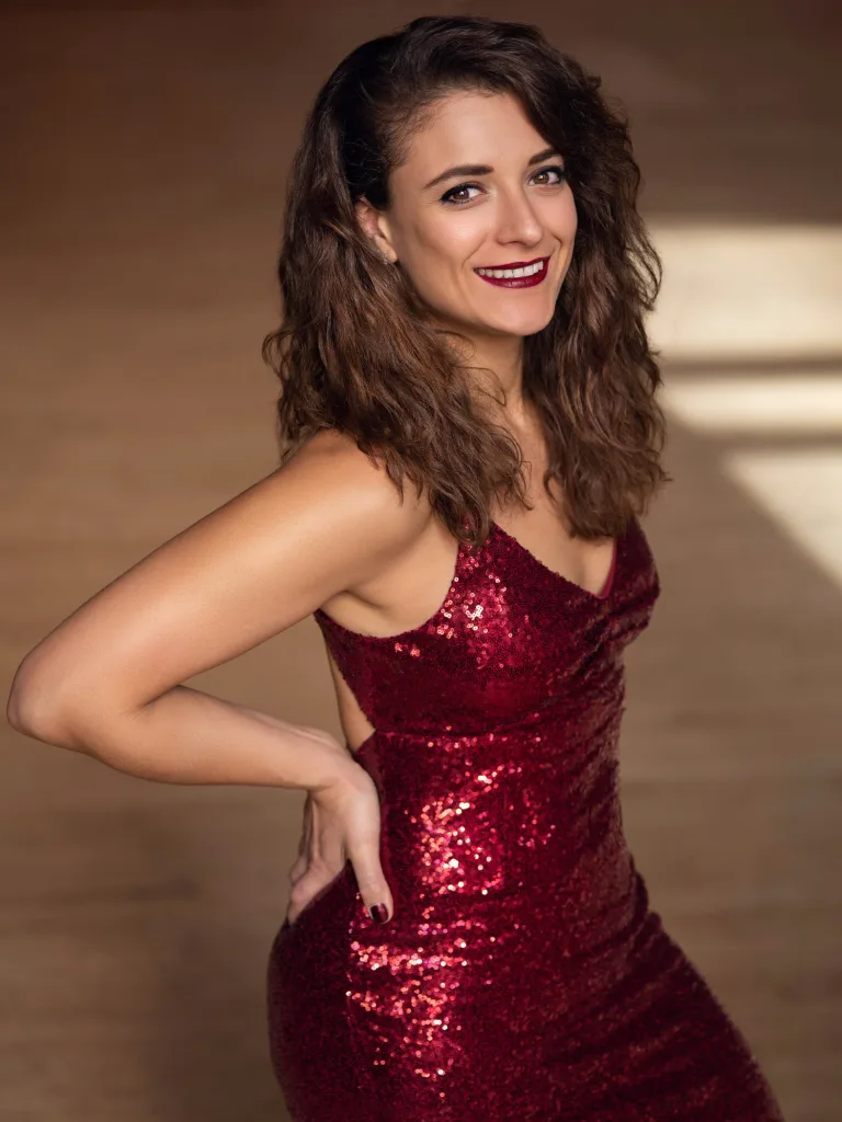A woman in a sparkly red dress smiles.
